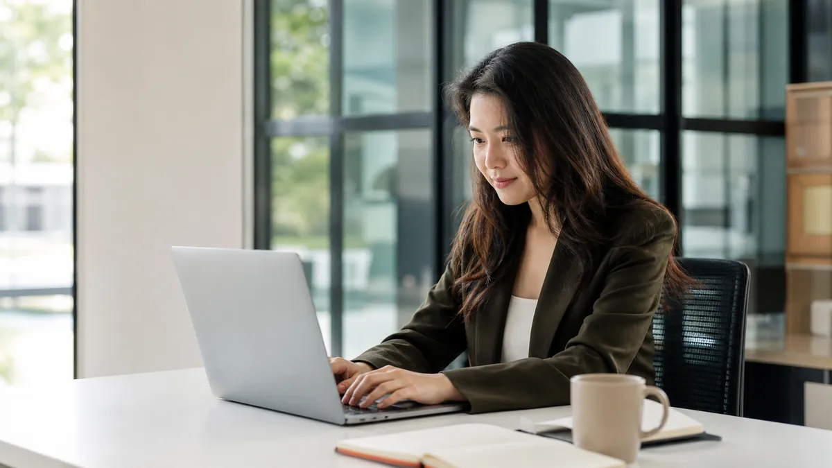 Customer success manager reviewing account notes with a teammate at a laptop